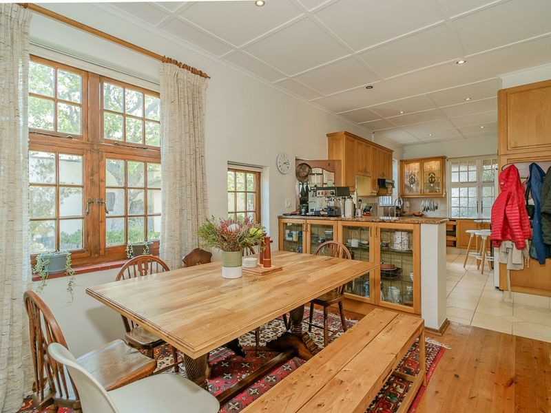Open-plan kitchen and dining area featuring timber cabinetry, granite countertops, coffered ceilings, and a mix of hardwood and tiled flooring.