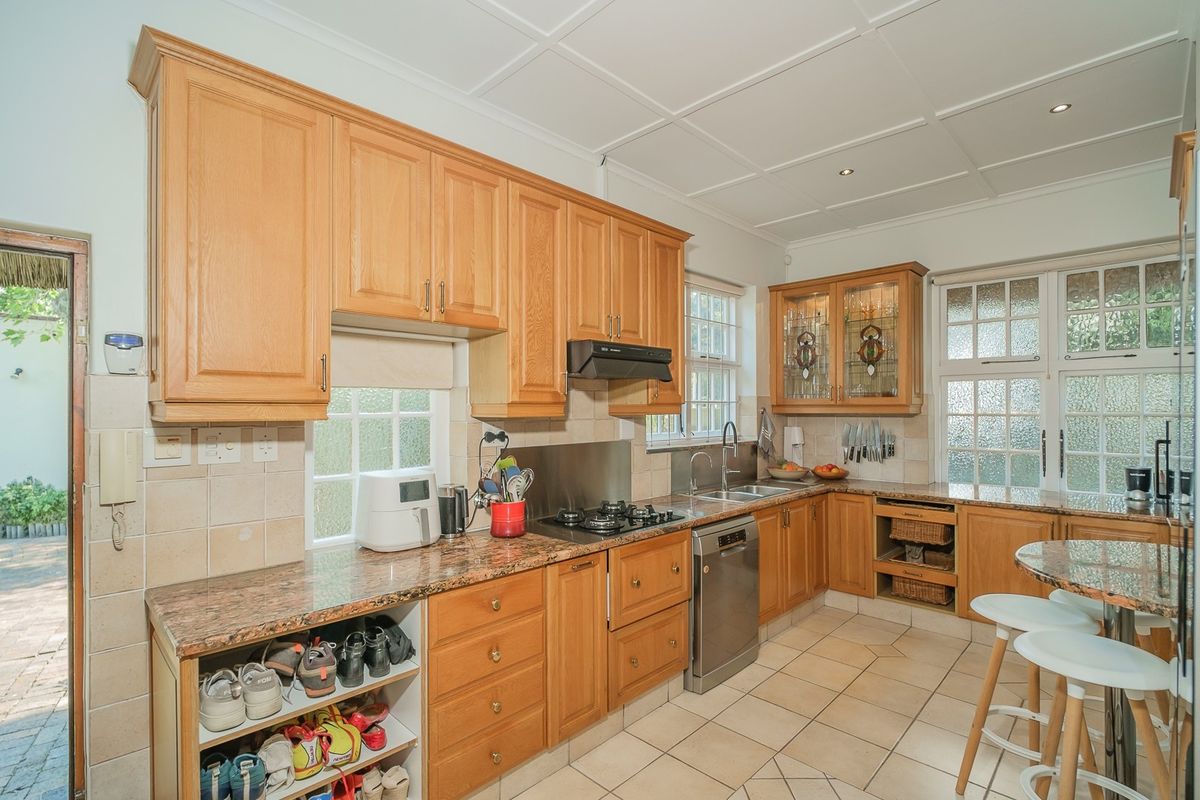 A functional kitchen featuring wooden cabinetry, granite countertops, a gas hob, and tiled flooring, offering a classic layout with ample storage and workspace.