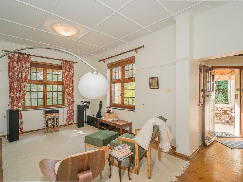 A living room featuring timber-framed windows, hardwood flooring, and a tiled ceiling, with direct access to an outdoor patio area.