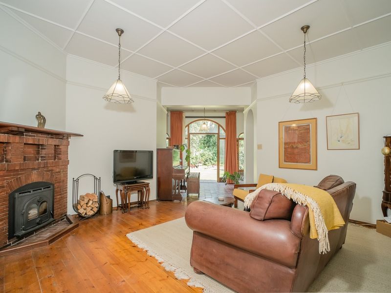 Spacious living room featuring a classic brick fireplace with a wood-burning stove, polished timber flooring, and a distinctive coffered ceiling.