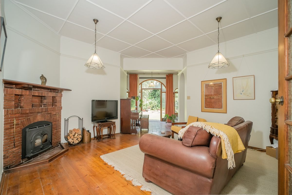 Spacious living room featuring a classic brick fireplace with a wood-burning stove, polished timber flooring, and a distinctive coffered ceiling.
