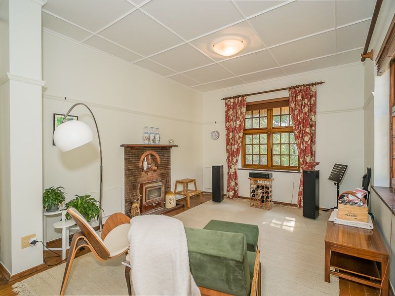 A cozy living room featuring a classic brick fireplace with a wood-burning stove, timber-framed windows, and a traditional tiled ceiling.