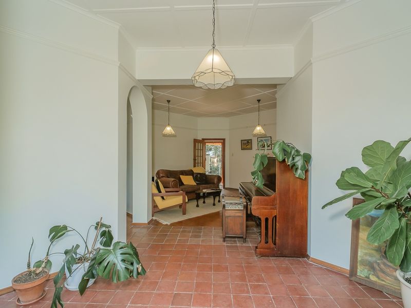 Spacious living area featuring classic terracotta floor tiles, an elegant archway, and high ceilings with decorative coving, creating a warm and inviting atmosphere.