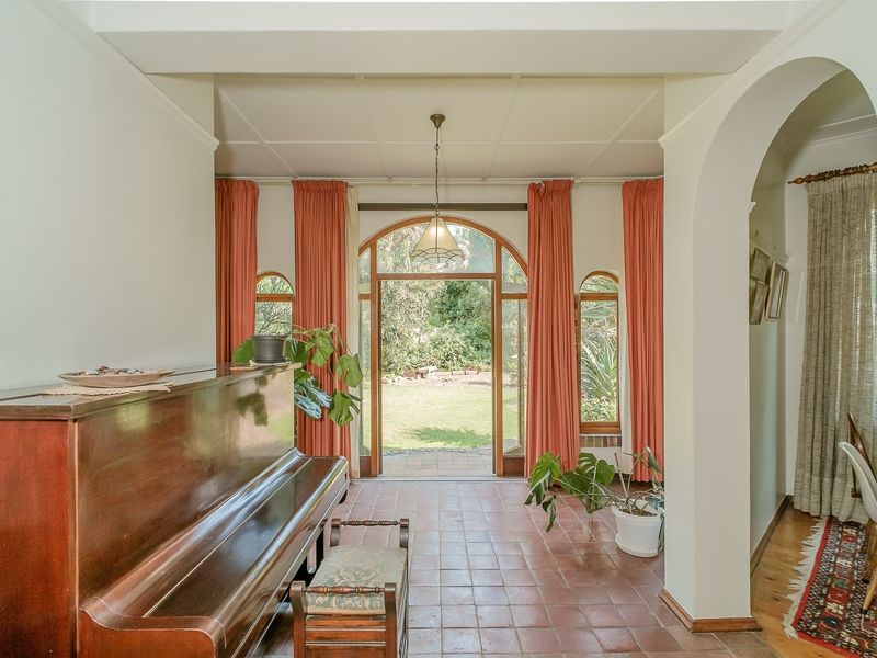 Welcoming entrance hall featuring terracotta tile flooring, an elegant arched glass door providing garden access, and a classic architectural archway.