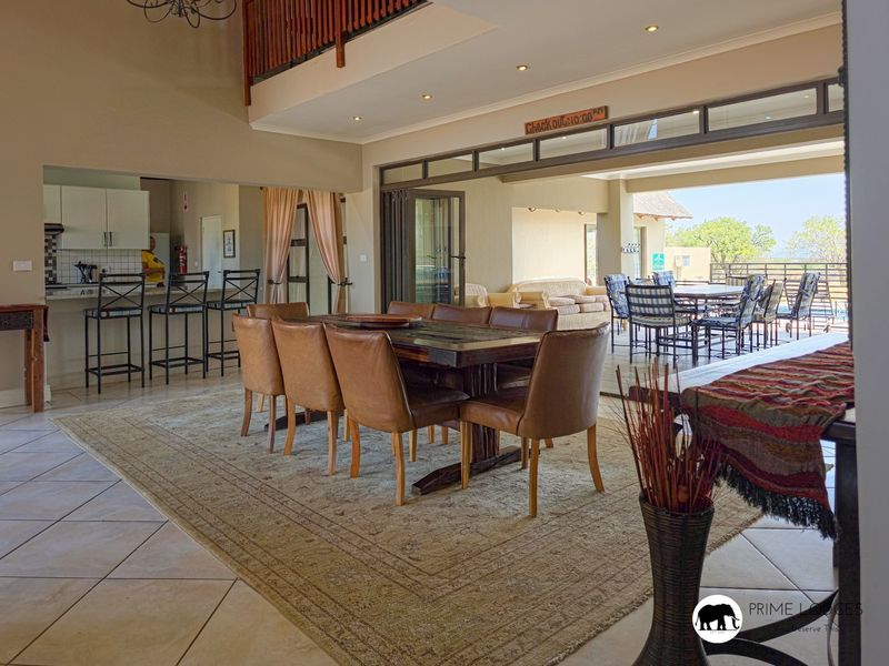 Spacious open-plan living and dining area featuring tiled floors, a modern kitchen with island, and seamless flow to the covered patio through stacking doors.