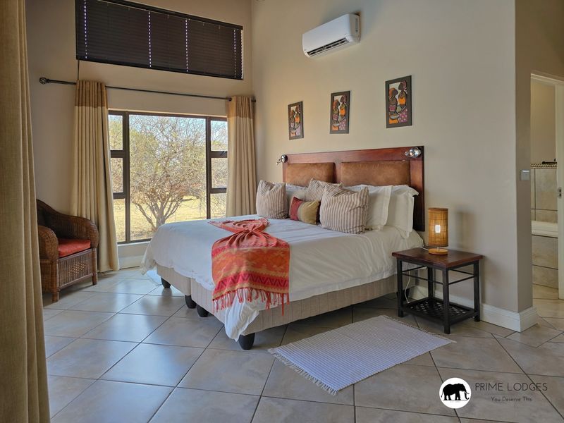 Spacious bedroom featuring tiled flooring, high ceilings, a split-system air conditioner, and large windows providing natural light and garden views.