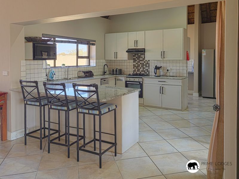 A functional kitchen featuring granite countertops, a breakfast bar, built-in cabinetry, and a gas hob with an extractor fan.