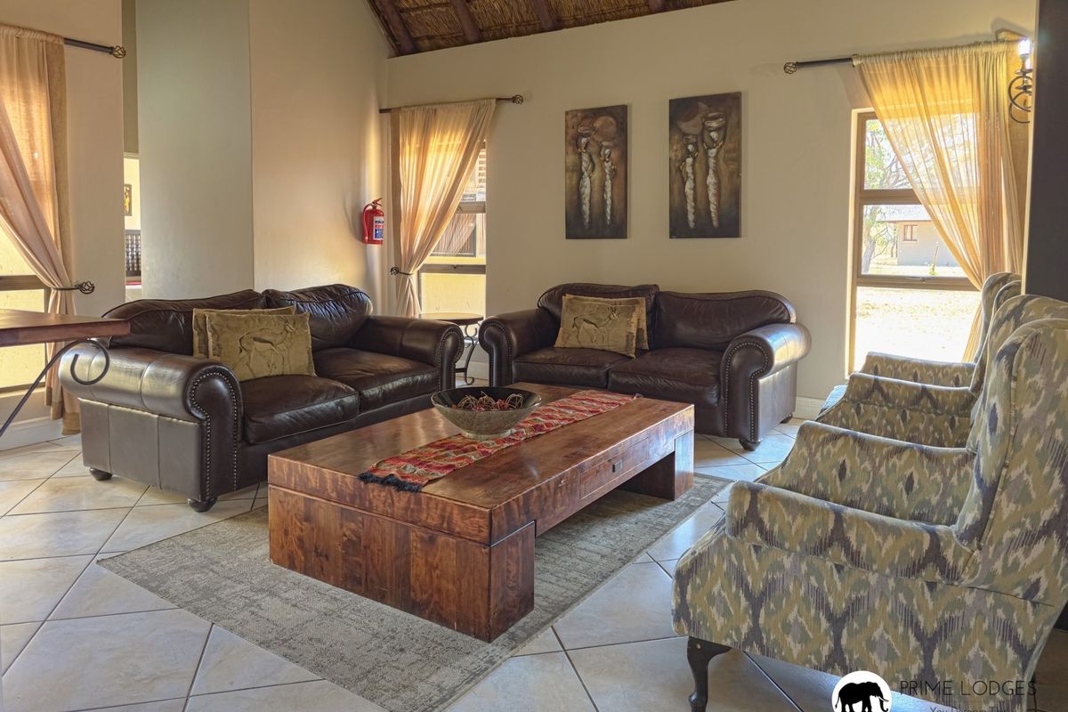 Spacious living room featuring a high vaulted thatched ceiling, neutral walls, and tiled flooring, creating a warm and inviting atmosphere.
