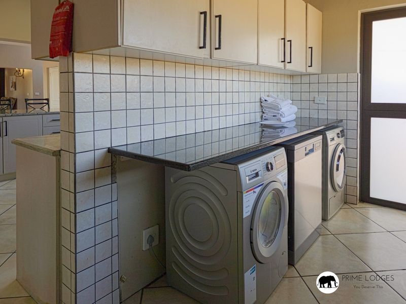Functional laundry area featuring built-in cabinetry, granite countertops, tiled splashbacks, and dedicated space for under-counter appliances with direct outdoor access.