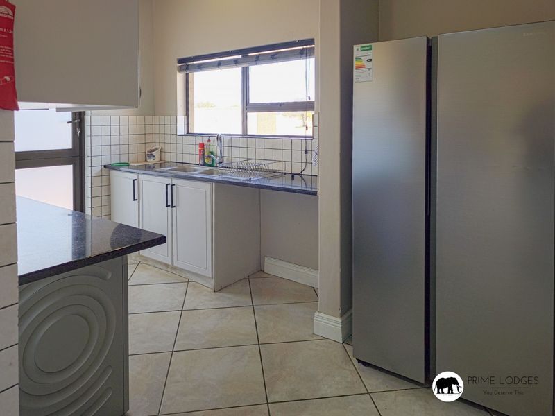 Functional kitchen featuring white cabinetry, granite countertops, tiled backsplash, and tiled flooring, providing a practical workspace with ample storage.