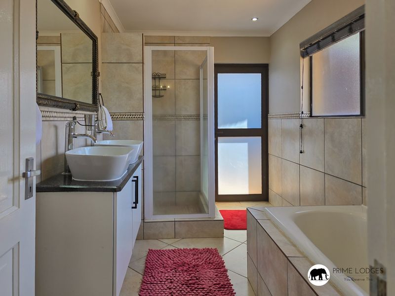 A well-maintained bathroom featuring a double vanity with vessel sinks, a separate shower enclosure, and a built-in bathtub with neutral tiling.