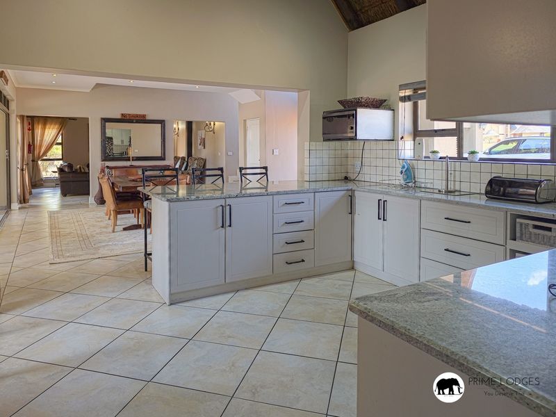 Spacious open-plan kitchen featuring granite countertops, ample cabinetry, and tiled flooring, seamlessly flowing into the adjacent dining and living areas.