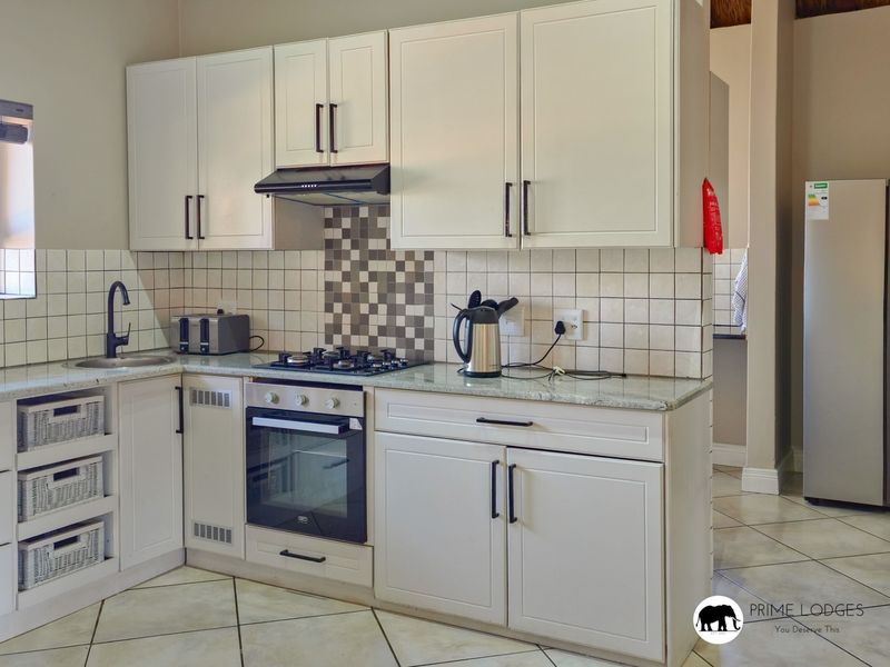 A well-maintained kitchen featuring white cabinetry, granite countertops, a gas hob, built-in oven, and a tiled backsplash.