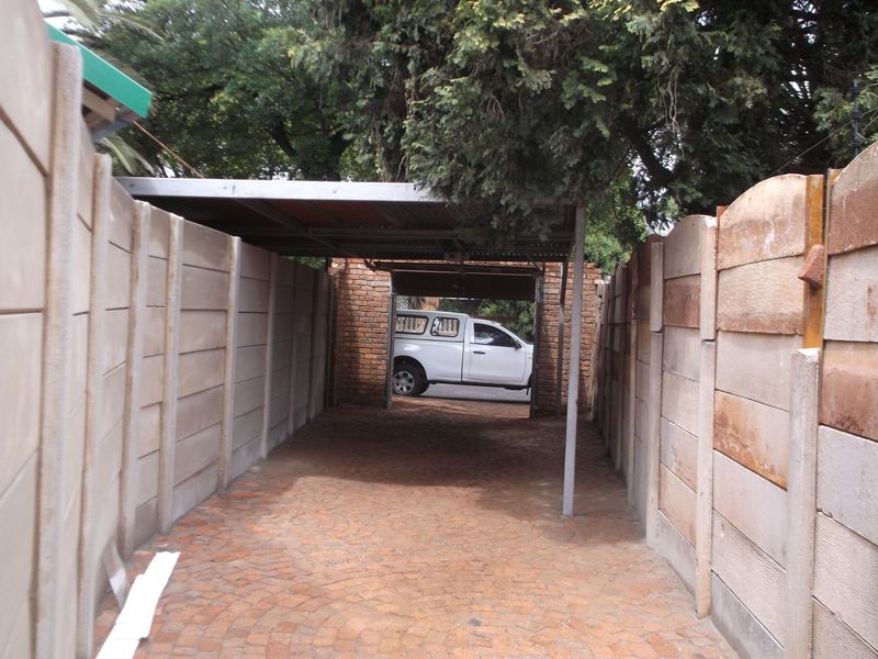 A covered carport area featuring precast concrete boundary walls and a paved driveway, providing secure off-street parking.