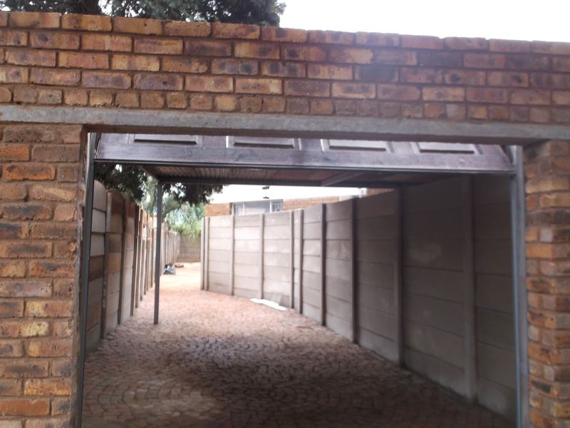 A view of a garage entrance featuring brick construction and precast concrete boundary walls with a paved driveway.