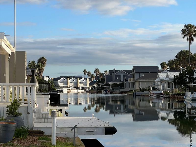 Scenic view of a tranquil canal with private jetty access and well-maintained waterfront landscaping in a residential estate.