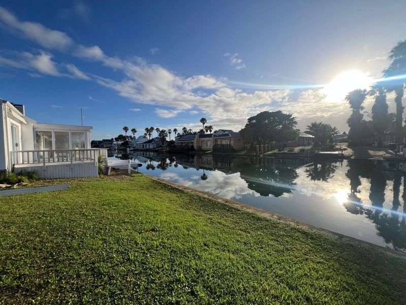 A scenic view of the waterfront canal with a well-maintained lawn and surrounding residential properties.