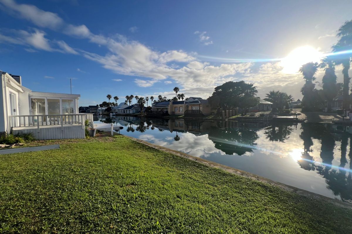 A scenic view of the waterfront canal with a well-maintained lawn and surrounding residential properties.