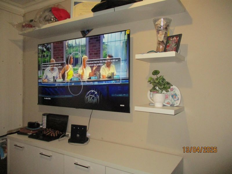 A living room area featuring wall-mounted floating shelves and built-in white cabinetry, providing functional storage and display space.