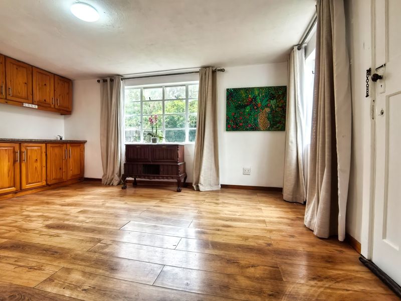 Open plan living area featuring warm laminate flooring, wooden cabinetry, and large windows that provide ample natural light.