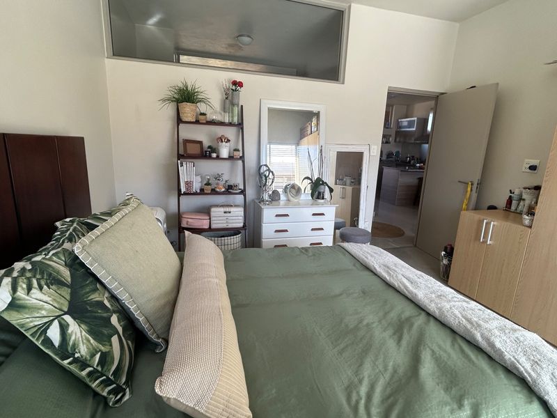 A bedroom featuring a transom window and access to an adjacent kitchen area, providing a functional layout with neutral wall finishes.