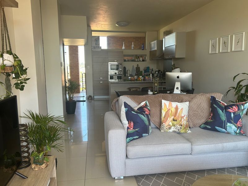 Open-plan living area featuring a modern kitchen with built-in appliances, granite countertops, and sleek cabinetry, flowing seamlessly into a comfortable lounge space.