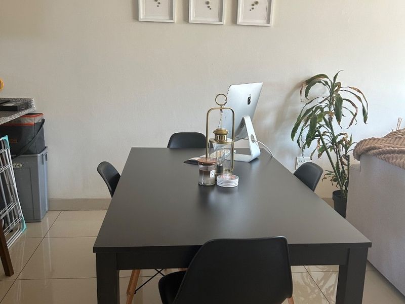 A dining area featuring neutral tiled flooring and a clean, minimalist wall finish, suitable for various interior design styles.