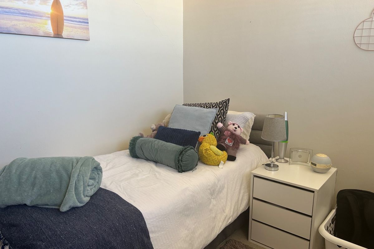 A compact bedroom featuring neutral wall finishes and a visible hairline crack on the upper wall surface.