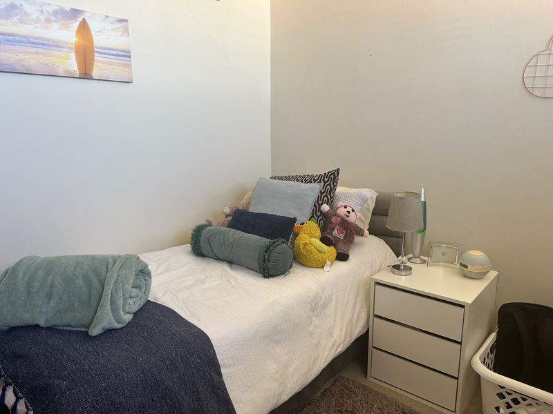 A compact bedroom featuring neutral wall finishes and a visible hairline crack on the upper wall surface.