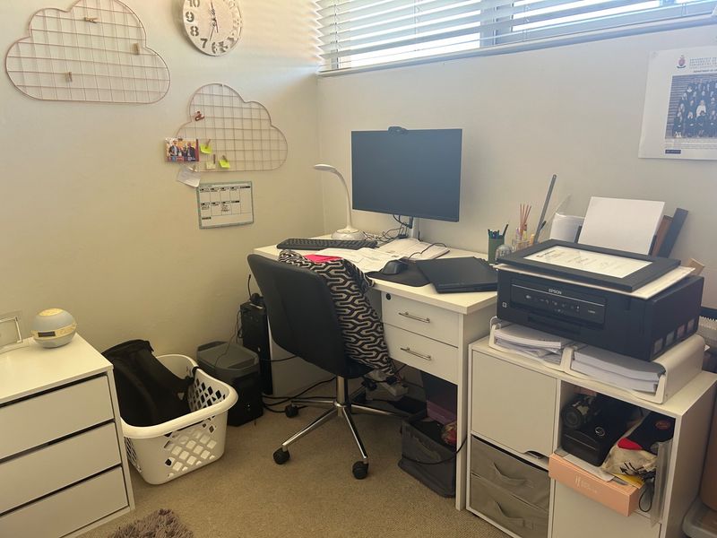 A functional home office space featuring carpeted flooring and venetian blinds, providing a dedicated area for work or study.
