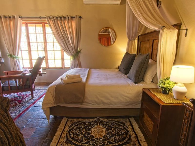 A cozy bedroom featuring terracotta tile flooring, a timber-framed window, and a wall-mounted air conditioning unit.