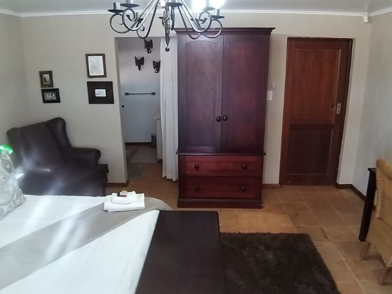 A well-maintained bedroom featuring tiled flooring, a solid wood door, and a classic chandelier light fixture.