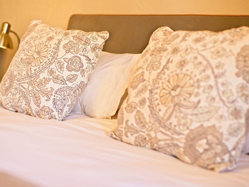 A close-up view of a bed with decorative pillows and a headboard.