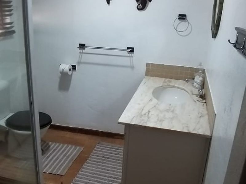 A functional bathroom featuring a vanity with a marble countertop, a separate shower enclosure, and tiled flooring.