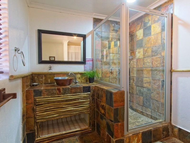 A rustic-style bathroom featuring a tiled shower enclosure, a custom vanity with a vessel sink, and natural stone tile finishes.