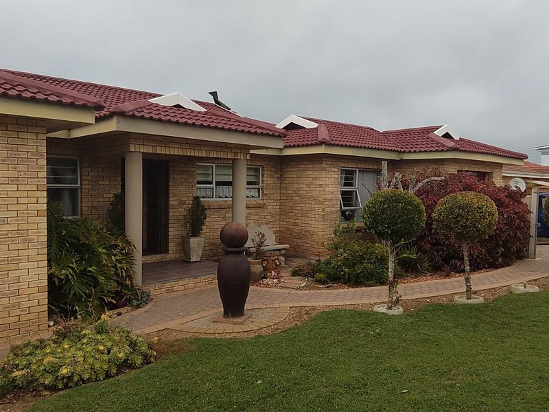 A well-maintained single-story brick house featuring a tiled roof, covered entrance, and a neatly landscaped front garden with a paved walkway.