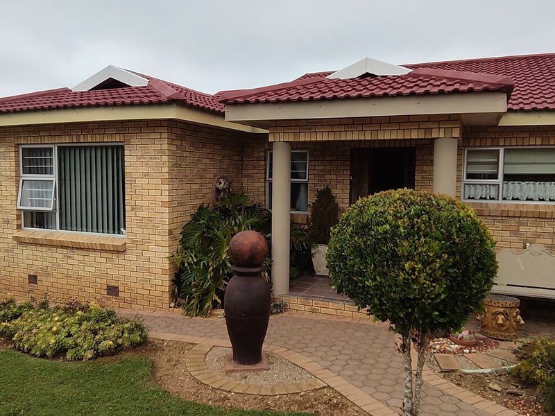 Front elevation of a face brick house featuring a tiled roof, covered entrance with concrete columns, and a paved walkway leading to the front door.