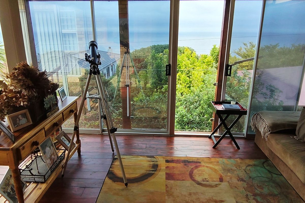 A living area featuring expansive sliding glass doors that provide natural light and views of the surrounding greenery and ocean.