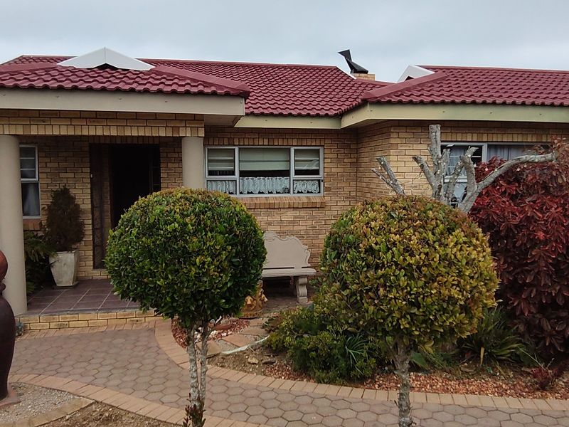 Front elevation of a brick house featuring a tiled roof, covered entrance porch with columns, and a paved walkway leading to the front door.