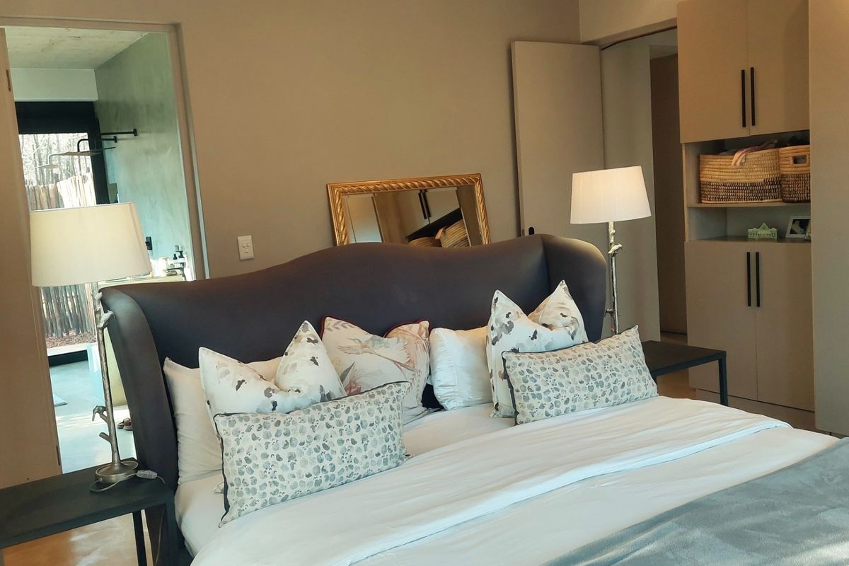 A well-maintained bedroom featuring neutral walls, built-in storage cabinetry, and an adjoining ensuite bathroom visible through the doorway.