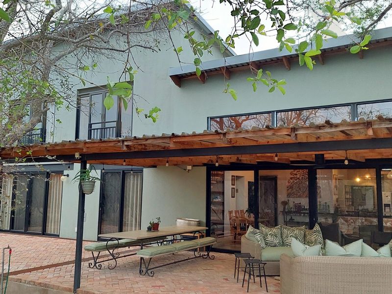Spacious covered patio featuring a timber pergola, brick paving, and large sliding glass doors providing seamless indoor-outdoor flow.