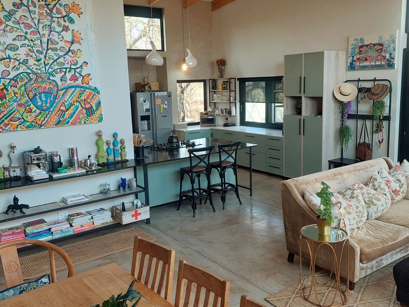 Spacious open-plan living area featuring a modern kitchen with island, polished concrete floors, vaulted ceilings, and seamless access to the outdoor space.