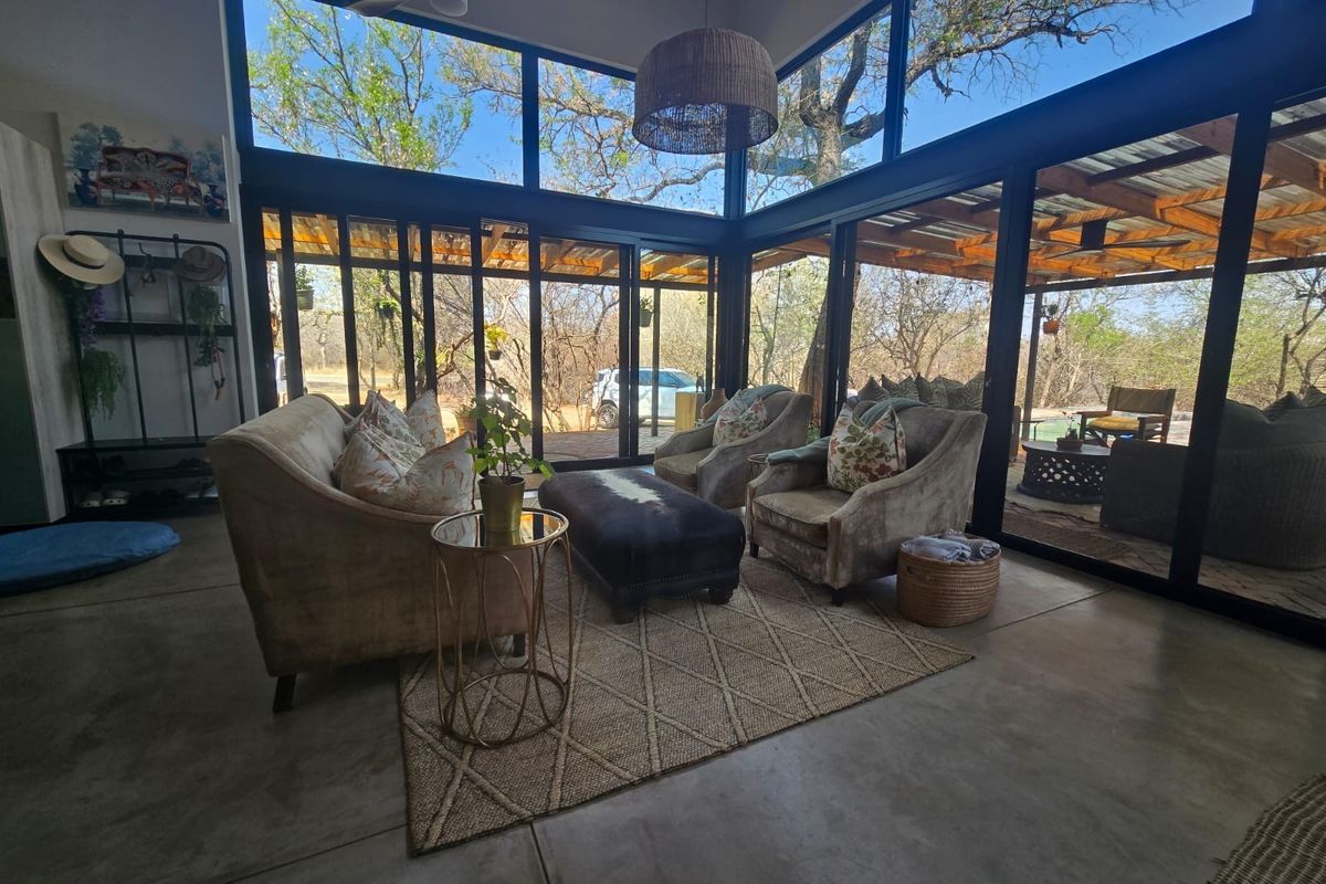 Modern living area featuring polished concrete floors and expansive floor-to-ceiling glass walls that provide seamless integration with the surrounding natural landscape.
