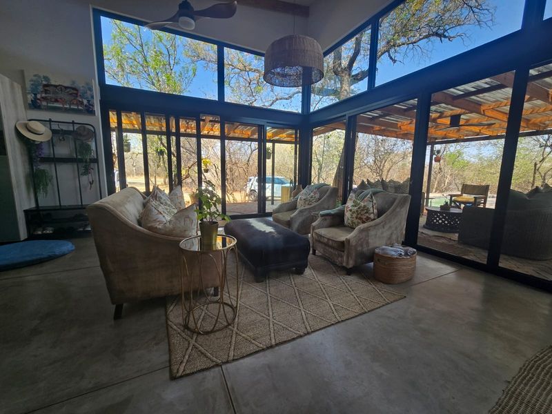 Modern living area featuring polished concrete floors and expansive floor-to-ceiling glass walls that provide seamless integration with the surrounding natural landscape.