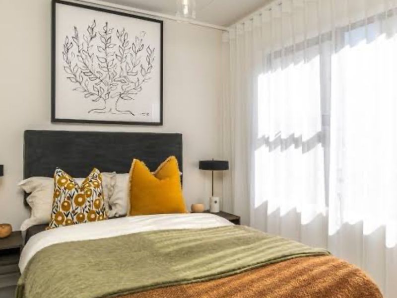 A well-lit bedroom featuring neutral walls, a pendant light fixture, and floor-to-ceiling curtain tracks.