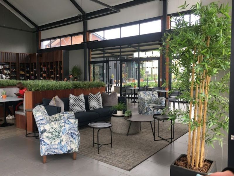 Spacious open-plan living area featuring high vaulted ceilings, exposed steel structural elements, and large glass doors providing ample natural light.