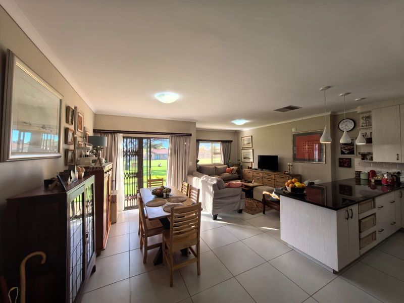 Spacious open-plan living area featuring a modern kitchen with granite countertops, tiled flooring, and seamless access to the outdoor space through sliding glass doors.