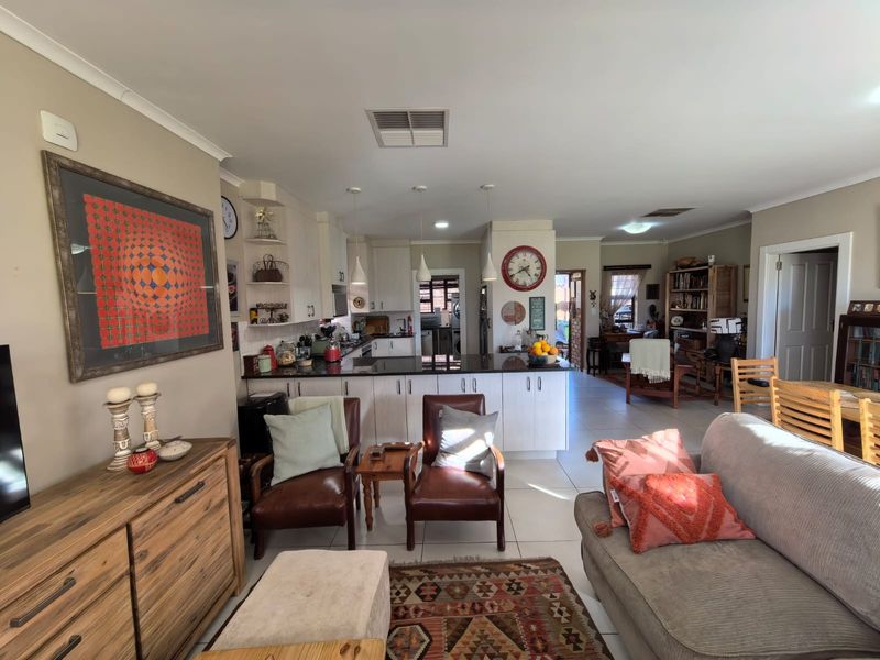 Spacious open-plan living and kitchen area featuring tiled floors, granite countertops, and ample built-in cabinetry, creating a functional and connected home layout.