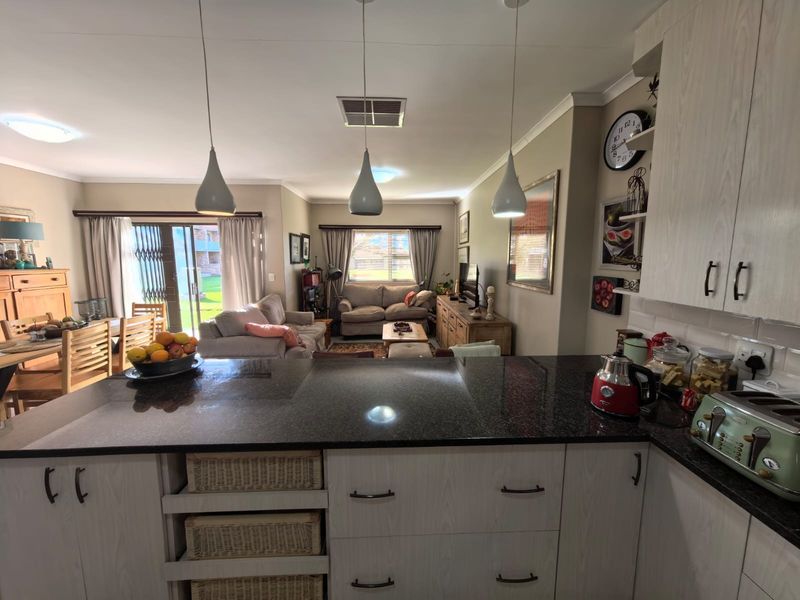 An open-plan living and kitchen area featuring a granite-topped kitchen island, pendant lighting, and sliding doors leading to an outdoor space.