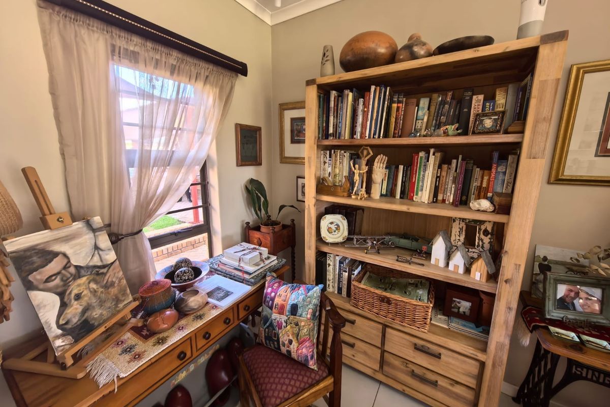 A cozy room featuring tiled flooring and cove cornicing, currently utilized as a study or hobby space with natural light from the window.
